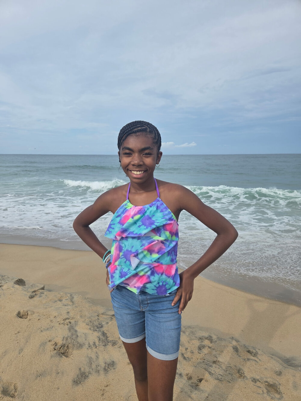 Zeni, the maker behind Crews Cakes Crafts and More, smiling on the beach with the ocean behind her